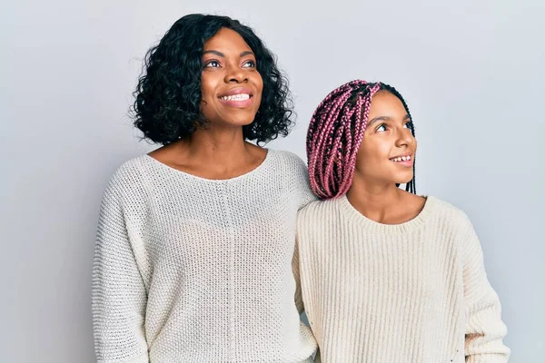 美しいアフリカ系アメリカ人の母親と娘がカジュアルな服を着て 顔に笑顔で横に見て抱きつく 自然な表情 自信を持って — ストック写真