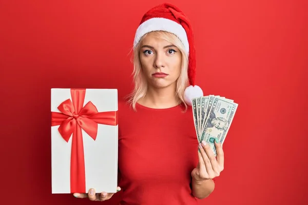 Young Blonde Girl Wearing Christmas Hat Holding Gift Dollars Relaxed — Stock Photo, Image