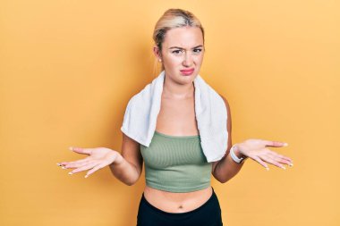 Spor kıyafetleri ve havlu giyen genç sarışın kız habersiz ve kolları açık, hiçbir fikri yok.. 