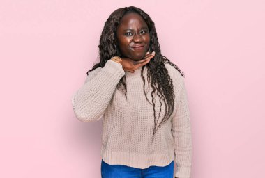 Yün kazak giyen genç Afrikalı bir kadın bıçak niyetine boğazını kesiyor, saldırganlığı şiddetle tehdit ediyor. 