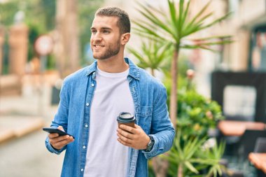 Kafkasyalı genç adam akıllı telefon kullanıyor. Şehirde kahve içiyor..