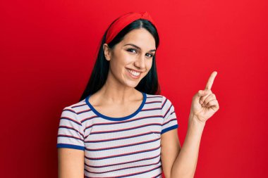 Gündelik kıyafetler giyen genç İspanyol kadın gülümsüyor mutlu bir şekilde elini ve parmağını yana uzatıyordu. 