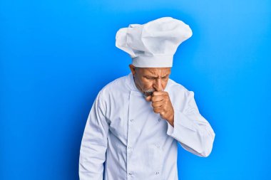 Orta yaşlı, gri saçlı, profesyonel aşçı üniforması giyen ve kendini kötü hisseden şapkalı bir adam. Soğuk algınlığı veya bronşitin belirtisi olarak öksürüyor. sağlık hizmeti kavramı. 