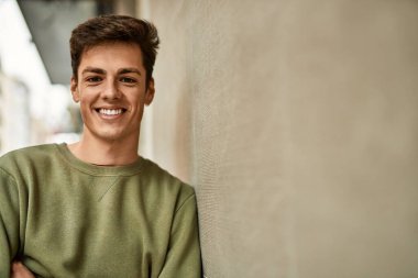 Genç İspanyol adam mutlu bir şekilde gülümsüyor şehirde çapraz hareketlerle.