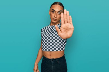 Makyaj yapan, uzun saçlı, modern kıyafetler giyen İspanyol transseksüel adam avucunun içi gibi şarkı söylemeyi kesiyor. Yüzünde olumsuz ve ciddi bir jest olan uyarı ifadesi. 