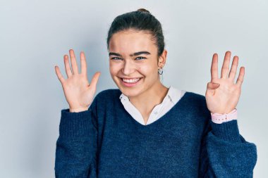 Gündelik kıyafetler giyen genç beyaz kız dokuz numarayı gösterip işaret ederken kendinden emin ve mutlu bir şekilde gülümsüyor.. 
