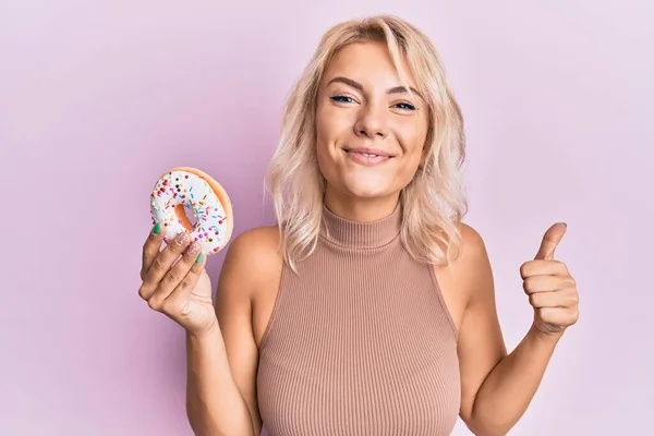 Ung Blond Flicka Håller Munk Ler Glad Och Positiv Tummen — Stockfoto