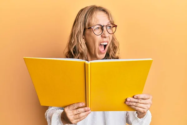 Middle Age Blonde Woman Reading Book Wearing Glasses Angry Mad — Stock Photo, Image