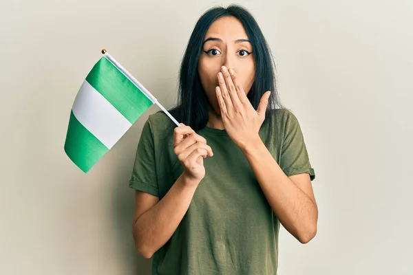 Menina Hispânica Jovem Segurando Bandeira Nigéria Cobrindo Boca Com Mão — Fotografia de Stock