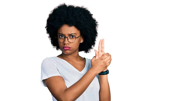 手のジェスチャーで象徴的な銃を保持カジュアルホワイトTシャツを身に着けている若いアフリカ系アメリカ人女性 シューティングゲームの武器を演奏 怒りの顔 — ストック写真