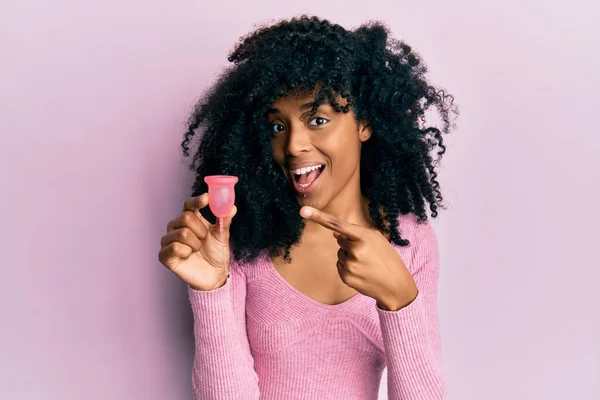 Afroamerykanka Afro Włosy Trzymając Kubek Menstruacyjny Uśmiechając Szczęśliwy Wskazując Ręką — Zdjęcie stockowe