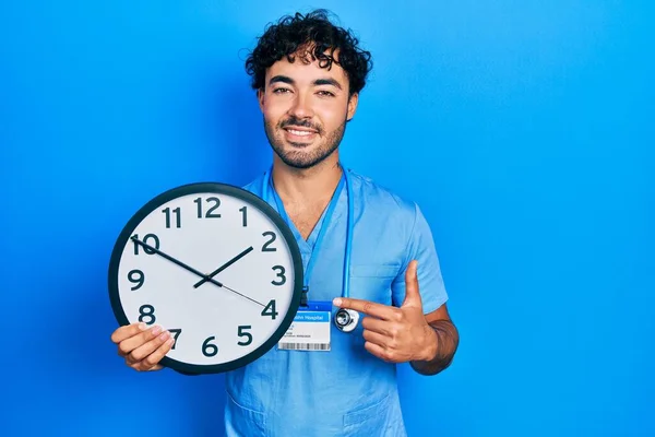 Jeune Homme Hispanique Portant Bleu Infirmière Uniforme Tenant Horloge Souriant — Photo