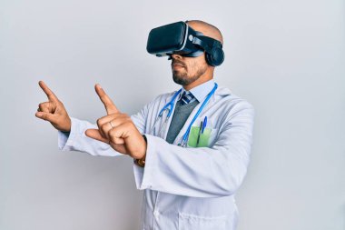 Üniforma giyen ve izole beyaz arkaplan üzerine 3D gözlük takan konsantre yüzlü genç Arap doktor..