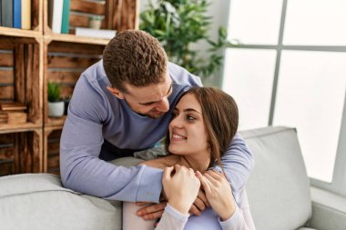 Kafkasyalı genç bir çift kanepede oturuyor ve evde sarılıyorlar..