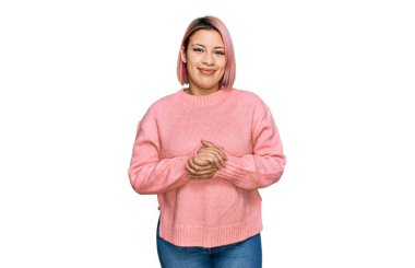 Pembe saçlı İspanyol kadın elleri çapraz parmaklı sıradan bir kazak giyiyor rahat ve neşeli gülümsüyor. Başarı ve iyimserlik 