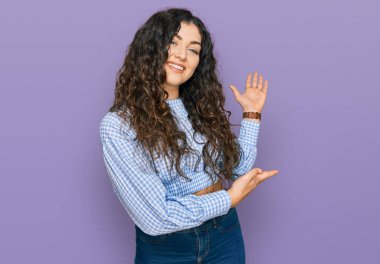 Günlük kıyafetler giyen genç İspanyol kız gülümseyerek doğal bir şekilde içeri girmeye davet ediyor. 