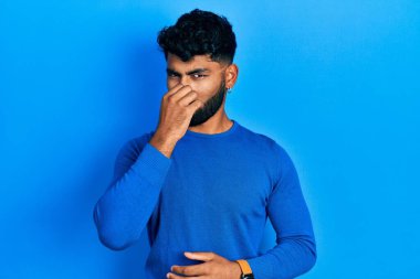 Sakallı, sıradan mavi süveter giyen, pis ve iğrenç bir koku alan, nefesini burnunda tutan Arap bir adam. Kötü kokuyor. 