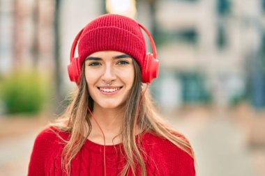 Şehirde kulaklık takan yün şapkalı genç İspanyol kadın..