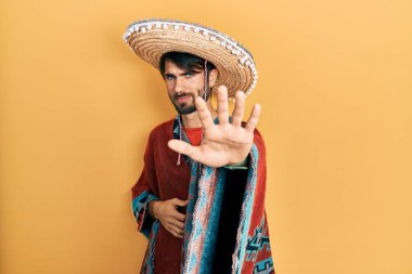 Meksikalı şapkalı genç İspanyol adam avucunun içi gibi şarkı söylemeyi kesiyor. Yüzünde olumsuz ve ciddi bir jest olan uyarı ifadesi. 