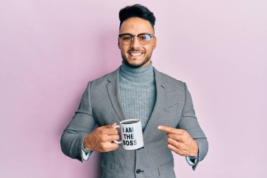 Genç Arap adam ben patron kahve fincanından içerken mutlu bir şekilde elini ve parmağını gösterdi. 