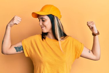 Genç İspanyol kadın teslimat üniforması giyiyor ve kollarında gururla gülümseyen kaslar var. fitness konsepti. 