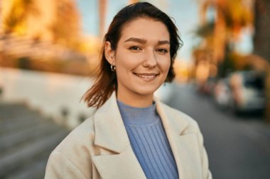 Genç İspanyol kadın gülümseyerek şehirde mutlu mesut dikiliyor.