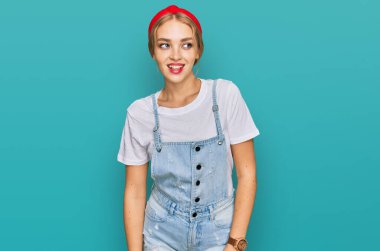 Kafkasyalı genç bir kız, günlük giysiler giyip yüzünde gülümsemeyle yan yana bakıyor, doğal bir ifade. Kendinden emin gülen. 