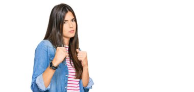 Genç esmer kadın gündelik giysiler giyiyor. Yumruk savunma hareketiyle dövüşmeye hazır. Kızgın ve üzgün yüz, sorundan korkuyor. 