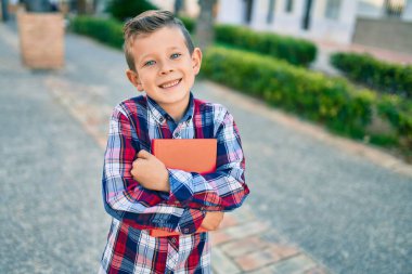 Sevimli beyaz çocuk gülümsüyor. Mutlu bir şekilde elinde kitap tutuyor..