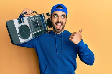 Kasetçalar tutan genç İspanyol adam, müzik dinliyor, başparmağını yana kaldırıyor, gülümsüyor ve ağzı açık. 