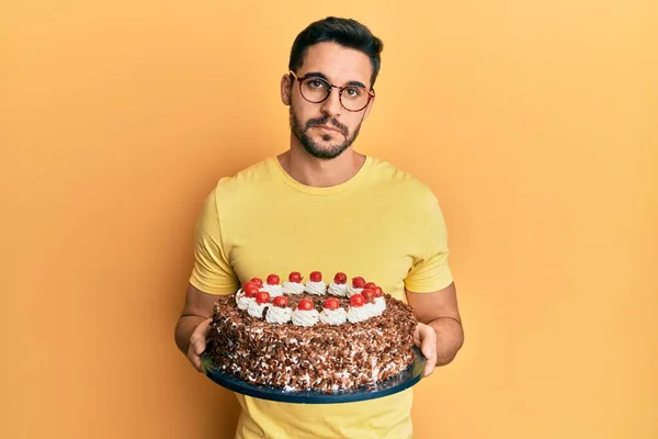Young Hispanic Man Holding Chocolate Cake Relaxed Serious Expression Face — Stock Photo, Image