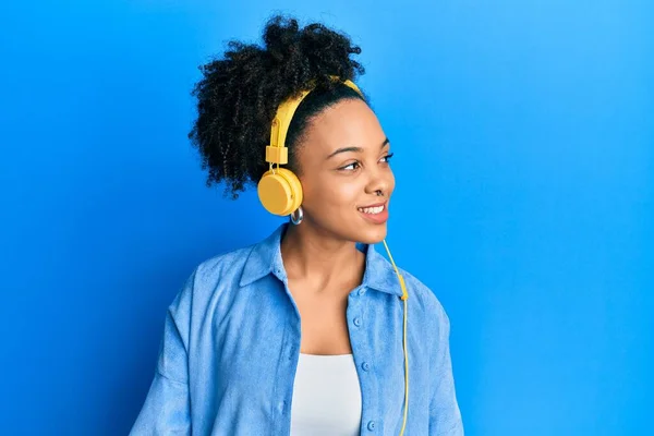 年轻的非洲裔美国女孩在听音乐时 用耳机把目光移开 面带微笑 表情自然 充满自信地大笑 — 图库照片