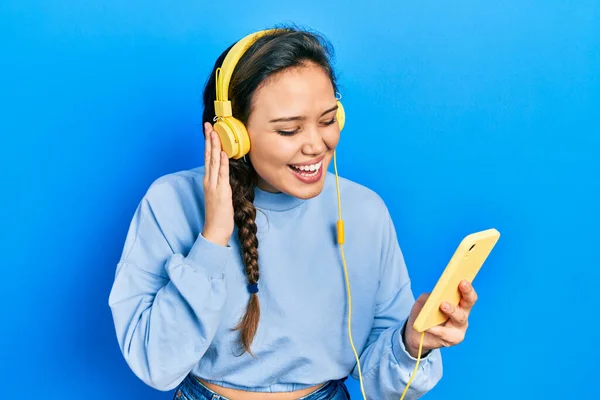 Chica Hispana Joven Usando Teléfono Inteligente Auriculares Celebrando Loco Sorprendido —  Fotos de Stock