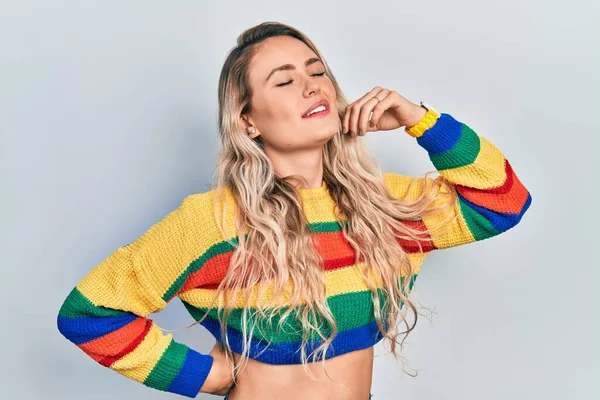 Smuk Ung Blondine Kvinde Iført Farvet Sweater Strækker Sig Tilbage - Stock-foto