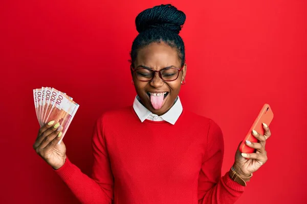 Joven Mujer Afroamericana Usando Teléfono Inteligente Sosteniendo Billetes Noruego Sacando —  Fotos de Stock