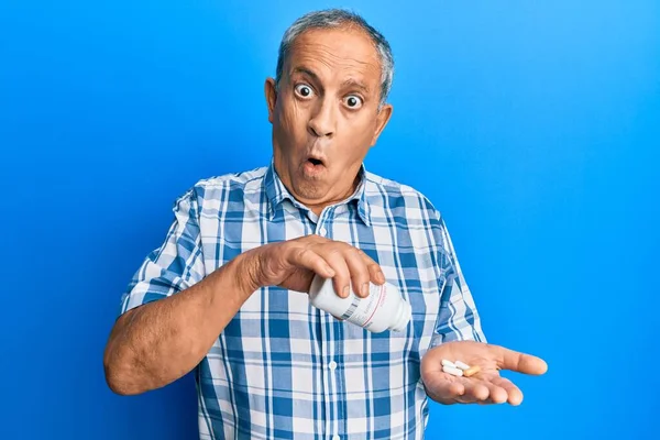 Homem Hispânico Sênior Segurando Pílulas Rosto Choque Parecendo Cético Sarcástico — Fotografia de Stock