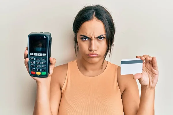 Młoda Brunetka Trzymająca Dataphone Kartę Kredytową Sceptyczna Nerwowa Marszcząca Brwi — Zdjęcie stockowe