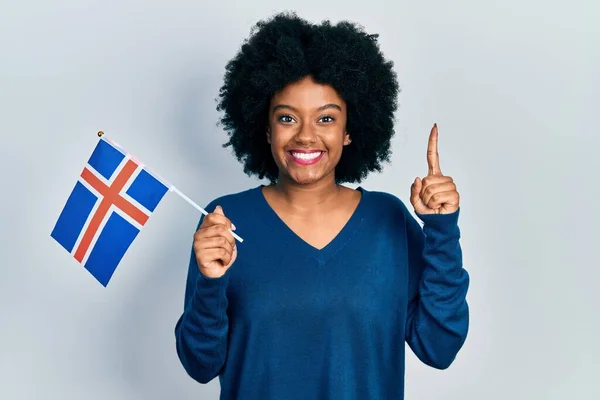 アイスランドの旗を持つ若いアフリカ系アメリカ人女性は 幸せな顔をしたアイデアや質問を指差す指で笑顔で ナンバーワン — ストック写真