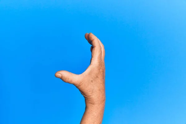 Hand Van Senior Spaanse Man Blauw Geïsoleerde Achtergrond Plukken Nemen — Stockfoto