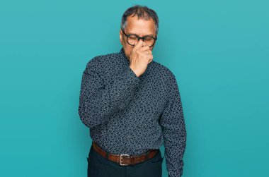 Orta yaşlı Hintli bir adam günlük kıyafetler ve gözlük takıp yorgun burnu ve gözleri ovuşturup yorgun ve baş ağrısı çekiyor. Stres ve hüsran kavramı. 