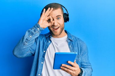 Kulaklık takan genç, beyaz bir adam gülümsüyor. Tamam imzayı atarken parmaklarının arasından bakıyor. 