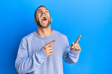 Kafkasyalı genç adam parmaklarını kenarı işaret ediyor kızgın ve kızgın çığlıklar atıyor sinirlenmiş ve öfkeli, öfkeyle bağırıyor.. 