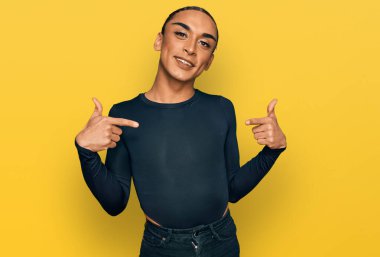 Makyaj yapan, uzun saçlı, sıradan giyinen, kendine güvenen, gülümseyen, kendini gururlu ve mutlu gösteren İspanyol bir transseksüel.. 