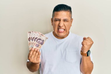 500 Meksika pesosu tutan genç Latin adam gururla bağırıyor, zaferi ve başarıyı kutluyor. 