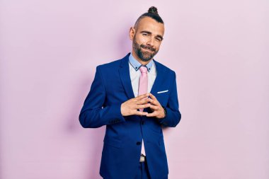 Genç İspanyol bir adam iş elbisesi giyip ellerini birbirine bağlıyor ve gülümseyerek gevşemiş ve neşeli olmasını diliyordu. Başarı ve iyimserlik 