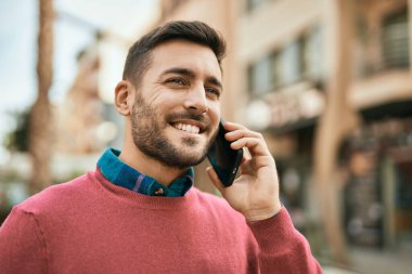Genç İspanyol adam gülümsüyor. Şehirdeki akıllı telefondan konuşuyor..