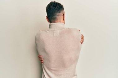 Balıkçı yaka kazak giyen İspanyol genç bir adam mutlu ve pozitif bir şekilde sarılıyor. Sevgi ve özgüven. 