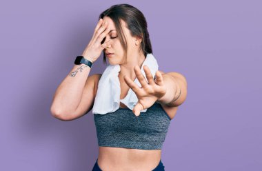 Spor kıyafetleri ve havlu giyen genç İspanyol kız elleriyle gözlerini kapatıyor ve üzgün ve korku ifadeleriyle jestleri durduruyor. utangaç ve olumsuz kavram. 
