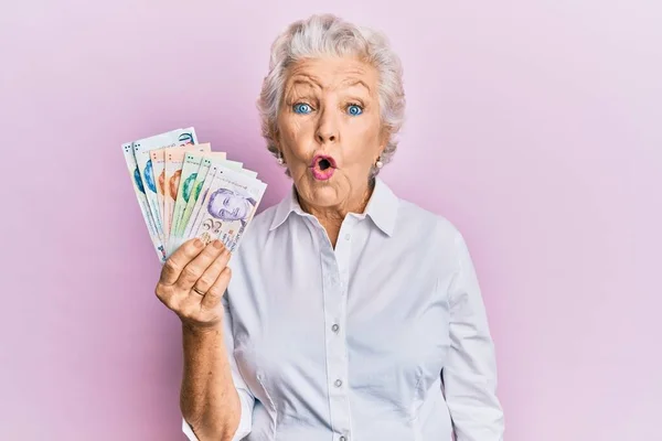 Женщина Старшими Седыми Волосами Держащая Банкноты Сингапорских Долларов Испуганная Изумленная — стоковое фото