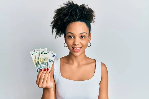 Młoda Afroamerykanka Trzymająca Banknotów Euro Wyglądająca Pozytywnie Szczęśliwie Stojąco Uśmiechnięta — Zdjęcie stockowe